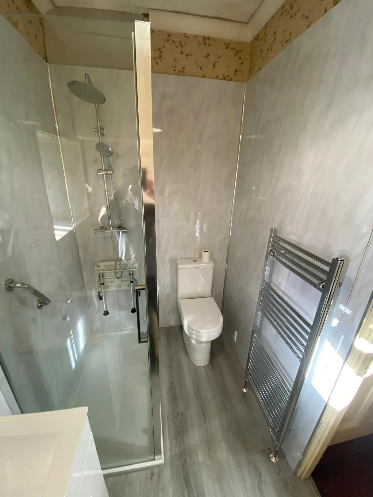 Compact shower room with a folding shower seat and chrome towel radiator