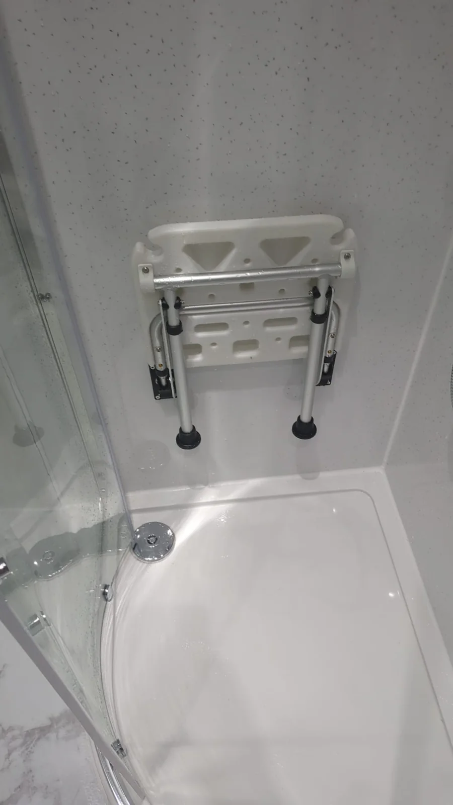 Fold-up shower seat above a white shower tray