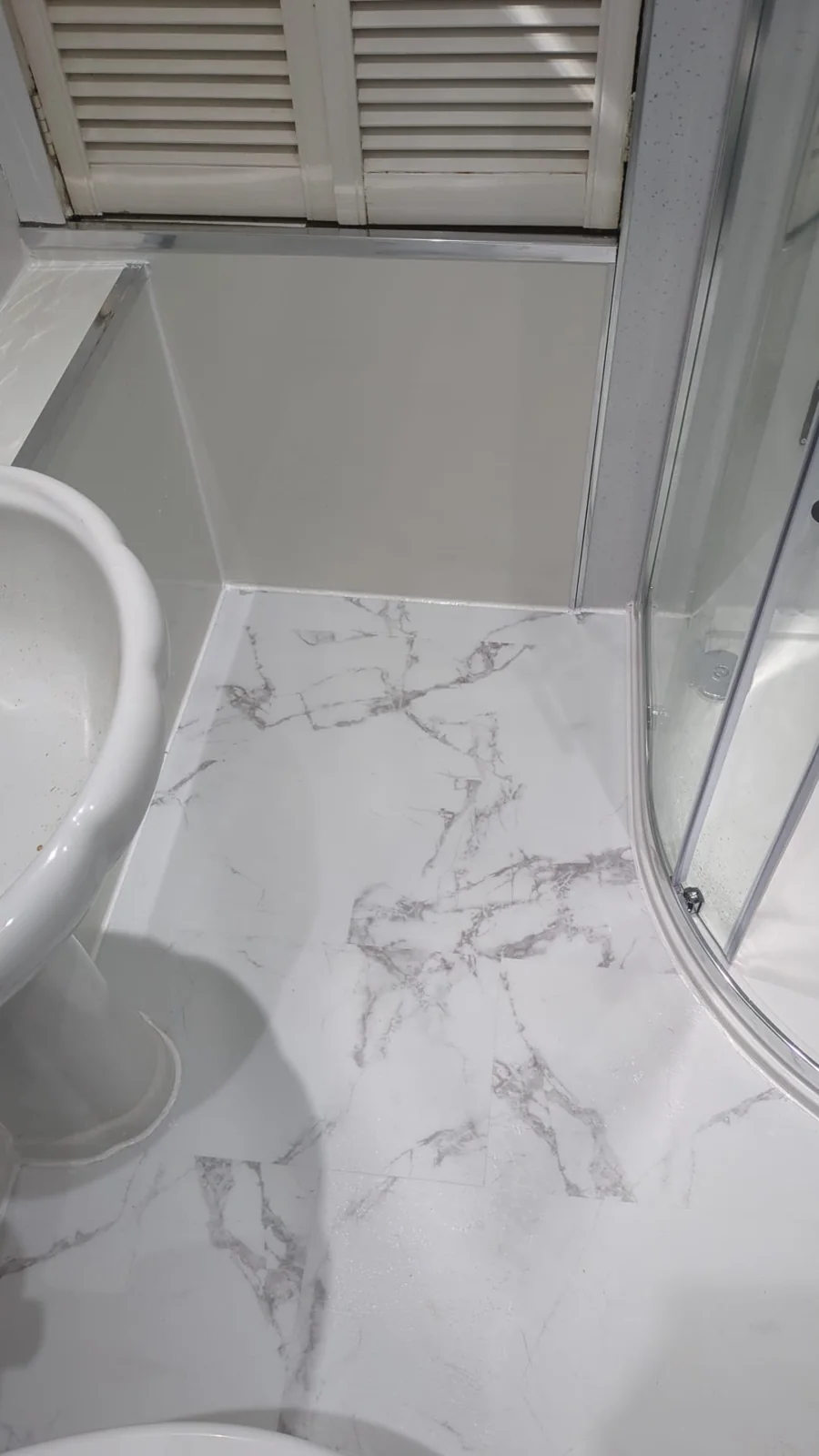 White marble-effect bathroom floor beside a pedestal basin and shower