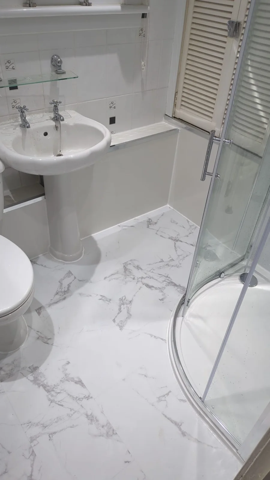 Pedestal basin and curved shower screen above a white marble-effect floor