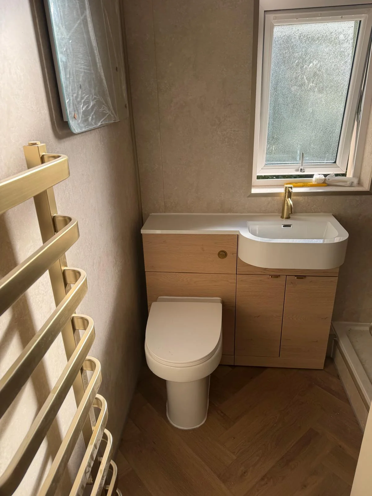Oak-effect vanity and toilet unit with gold fittings and herringbone flooring
