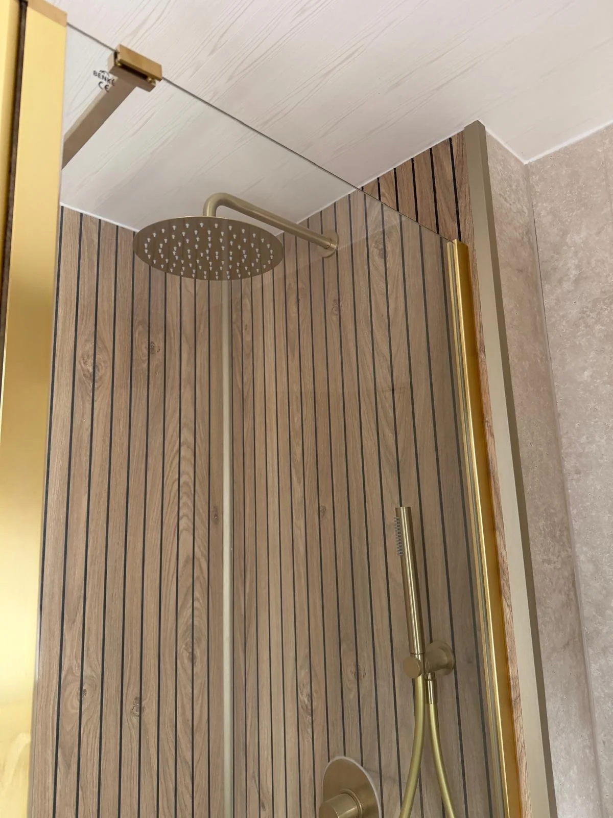 Gold rainfall shower head against wood-effect slatted wall panels