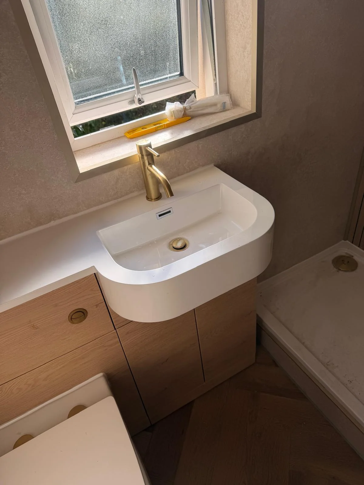 White basin and gold mixer tap above an oak-effect vanity