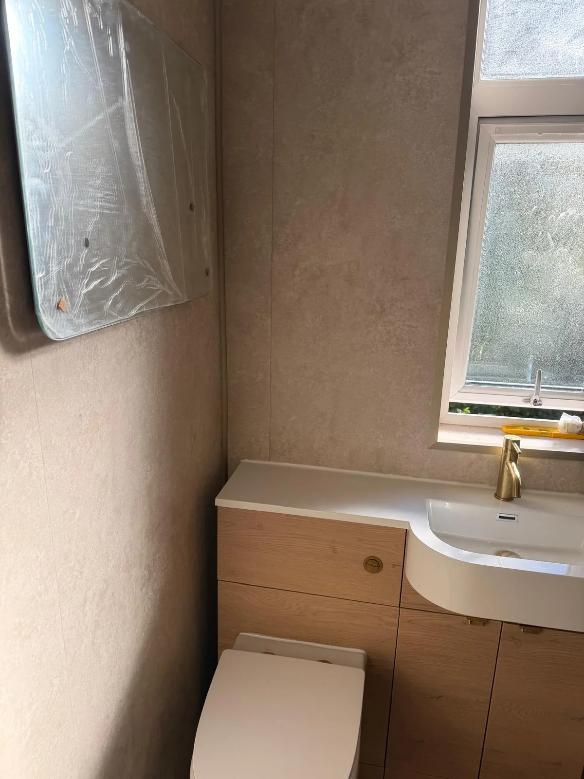 Oak-effect toilet and basin unit beneath a frosted window