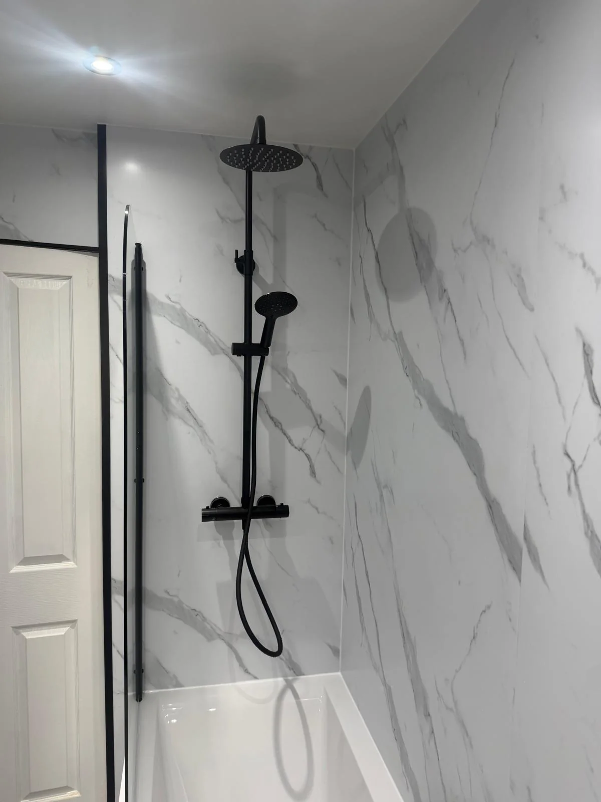 Black rainfall and handheld shower above a white fitted bath